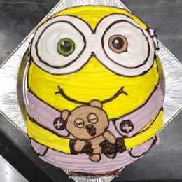 人形を持ったミニオンの顔型立体キャラクターケーキ 人形を持ったミニオンの顔型立体キャラクターケーキ